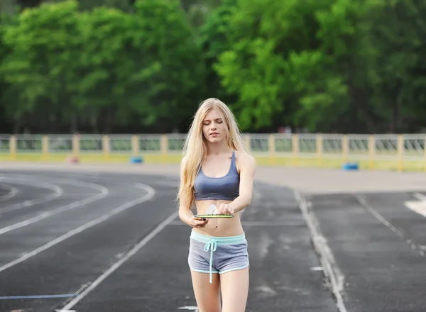 The beautiful sportswoman costs at stadium with racket and shuttlecock.