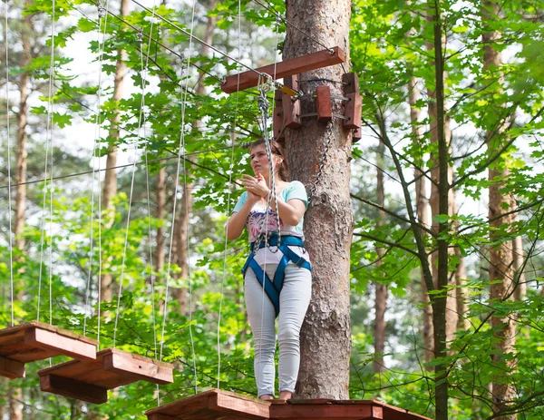 The woman climbs high trees in the wood.
