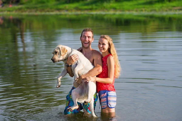 Happy couple and dog swim in the lake.