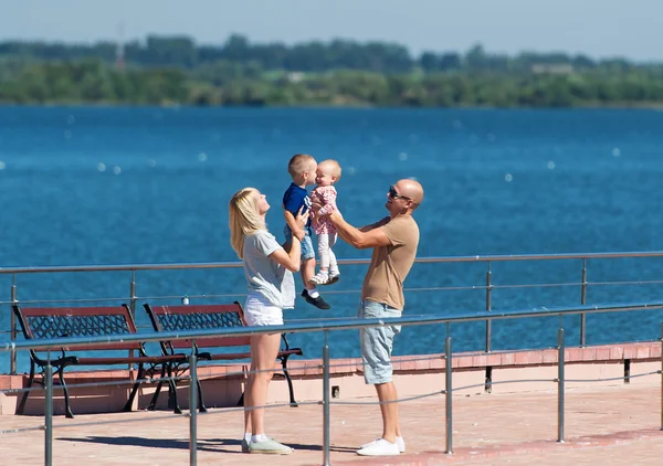 Happy family of four on stone jetty by the river