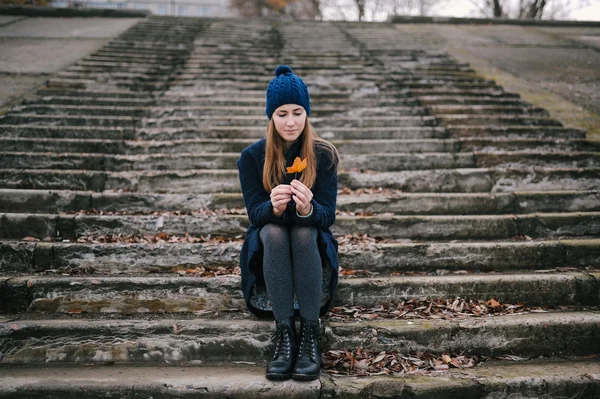 The girl in a blue cap sits on steps