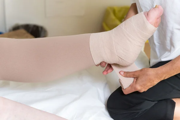 Woman bandaging patient\'s legs