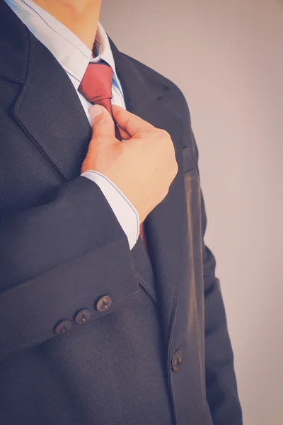 Portrait of business man in suit holding red tie