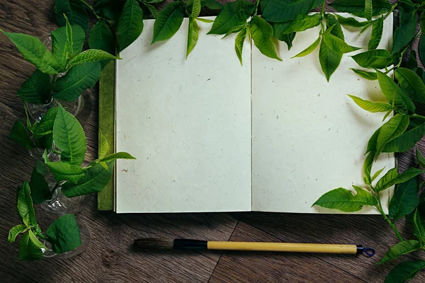The workplace painter  and green leaves. The presentation. The blank notebook. Spring time blank notebook. Background.