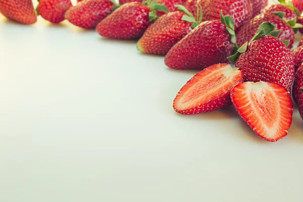 Cut strawberry on a white background. Sliced strawberry on strawberry background. Strawberry background. Macro. Texture.  Frame with copy space. Fruit background. Spring, summer background.