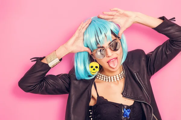 Funny girl with tongue stuck out wearing wig and sunglasses