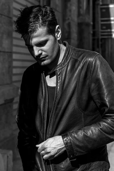 Man in the shadows wearing leather jacket and looking down