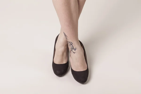 Girl with crossed feet wearing black heels shoes