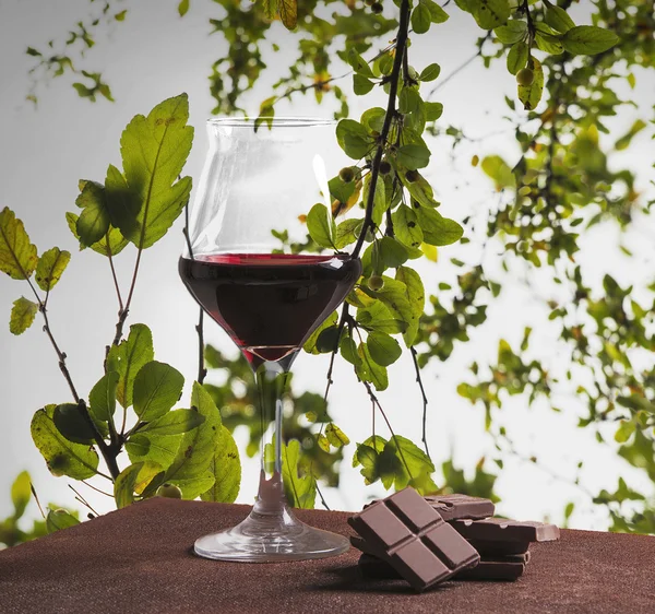 Red wine glass and chocolate with green leaves