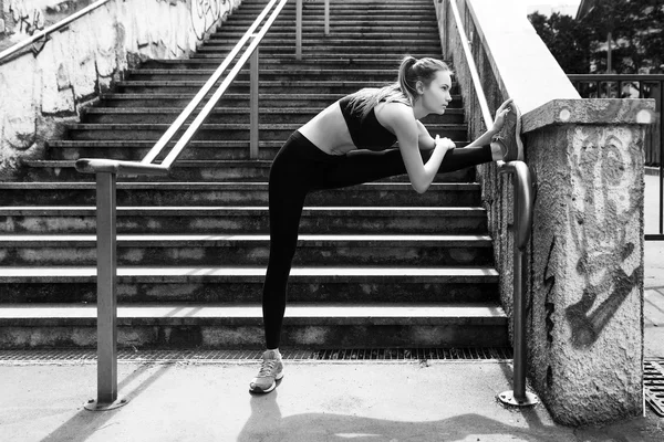 Athletic woman doing stretching in the city black and white