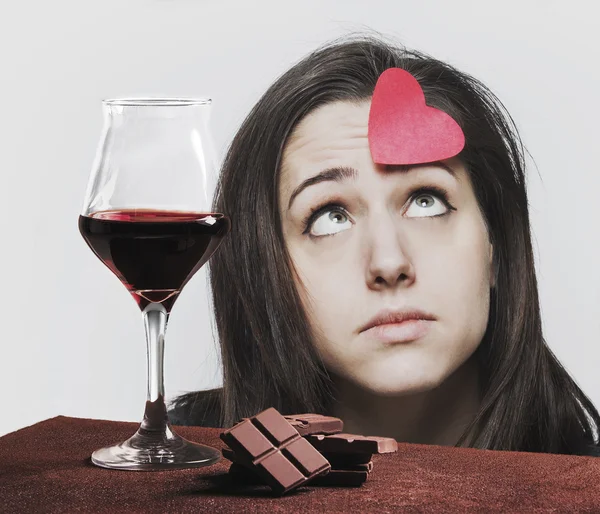 Wine glass with chocolate and sad girl thinking about love