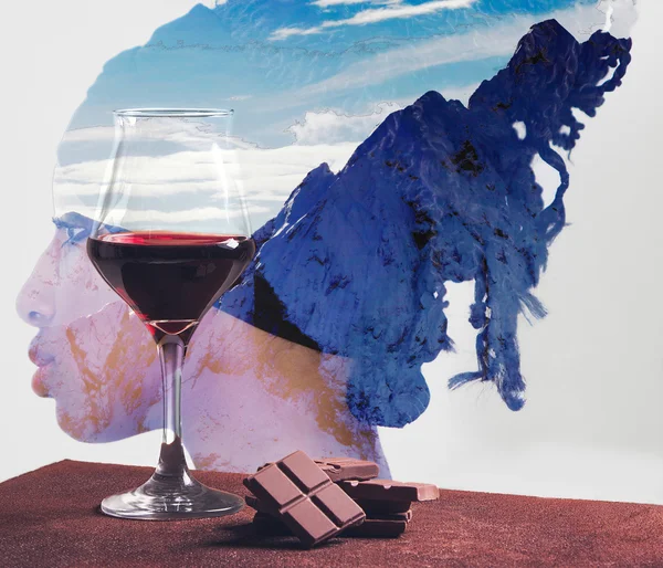 Red wine glass and chocolate with girl and mountains