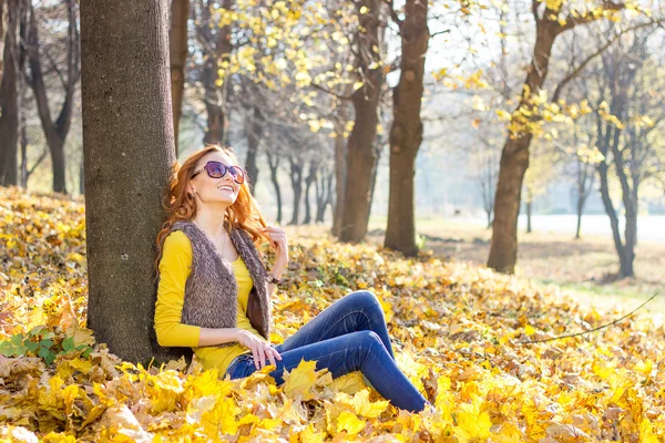 Young pretty woman in the park with photocamera in the autumn day