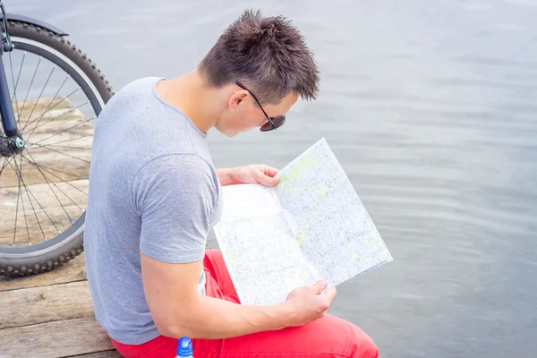 Young man, one happy tourist bicyclist with route map wearing in gray shirt with glasses