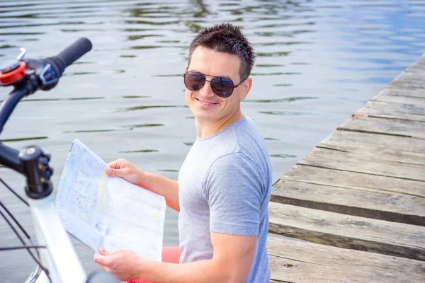 Young man, one happy tourist bicyclist with route map wearing in gray shirt with glasses