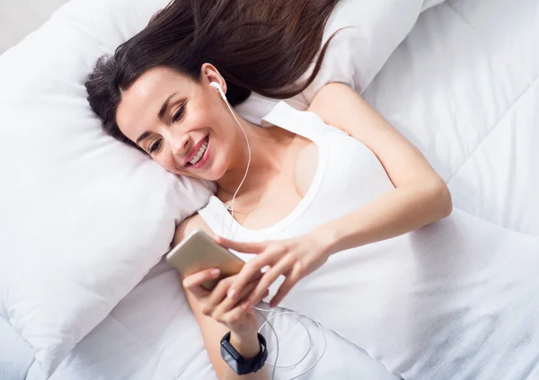 Cheerful delighted  woman resting in bed