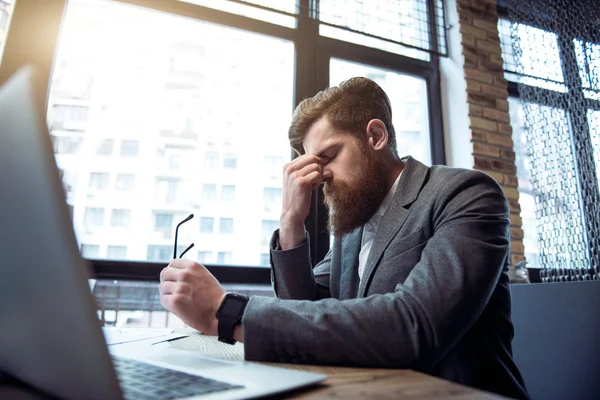 Cheerless  bearded man sitting at the table