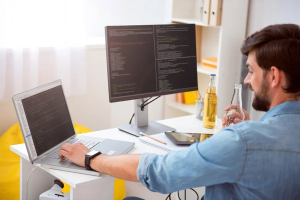 Man having drink while programming on laptop