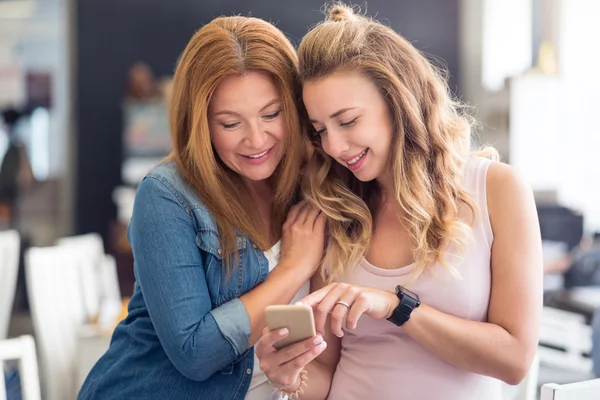Pleasant smiling mother and daughter using cell phone