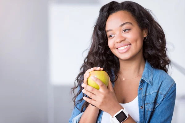 Positive young woman holding an apple.