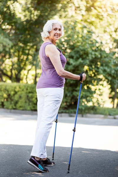 Full length figure of elderly woman with walking sticks