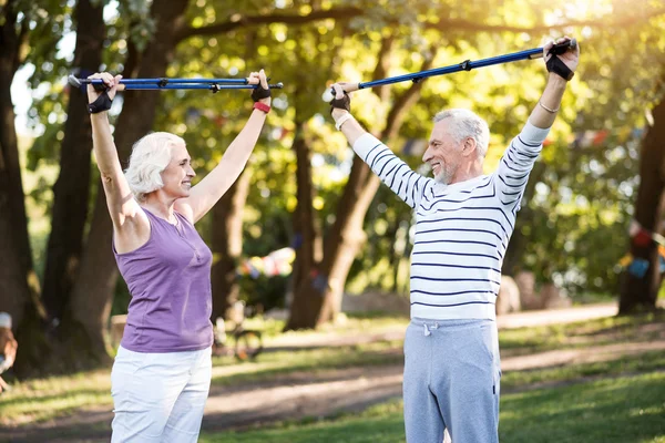 Good productive physical training of elderly couple in summer park