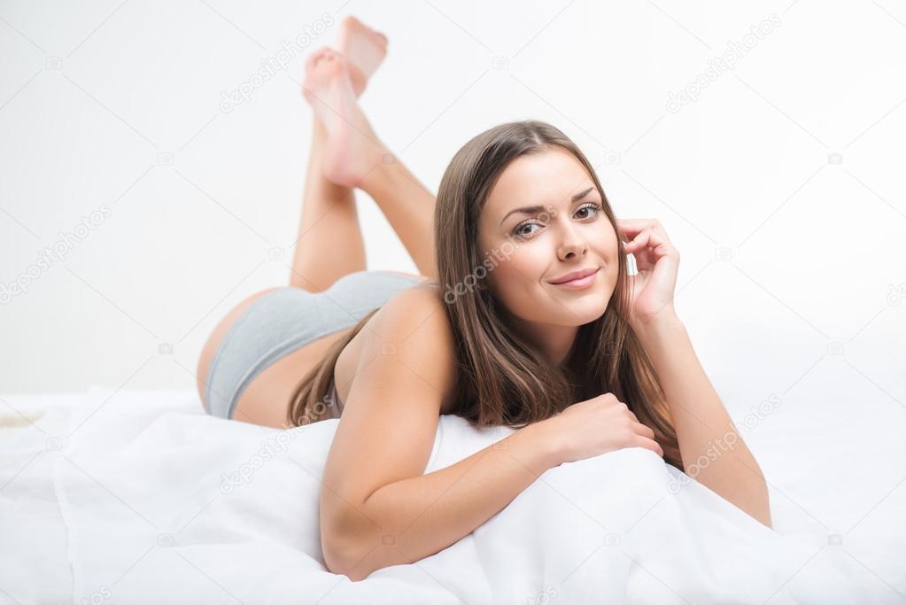 Студентка снимает лифчик на кровати