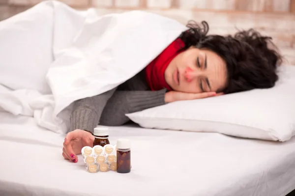Frustrated woman lying in bed with pills