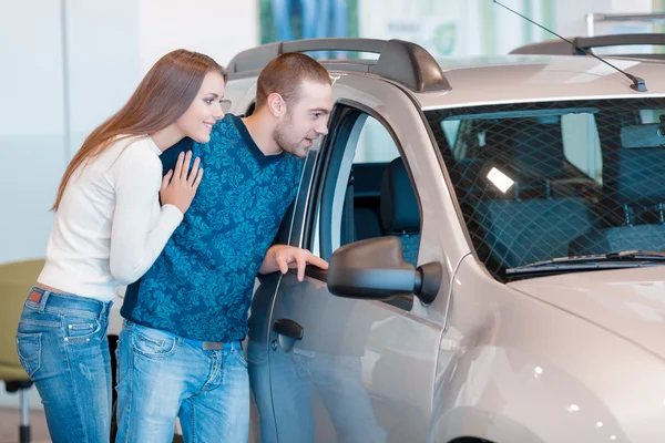 Interested couple examines a new car in showroom