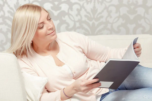 Woman reads magazine at home