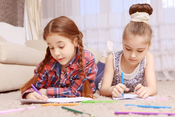 Two little girls lying on carpet