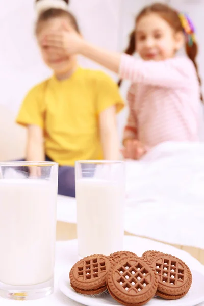 Children standing behind cookies and milk