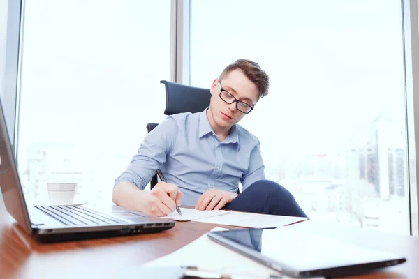 Young businessman filling papers in office