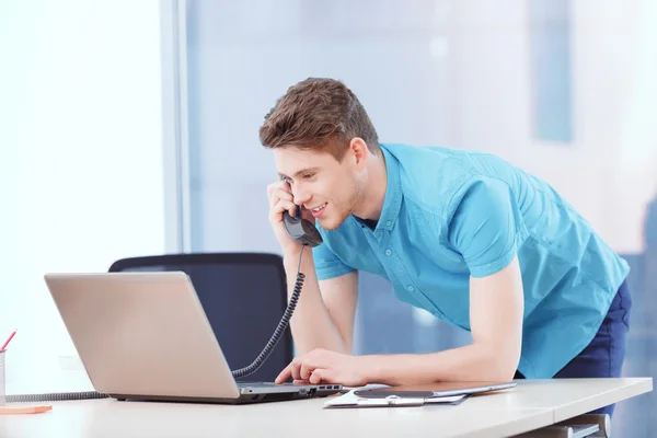 Youthful businessman standing near desk