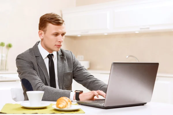 Man in suit working on computer kitchen