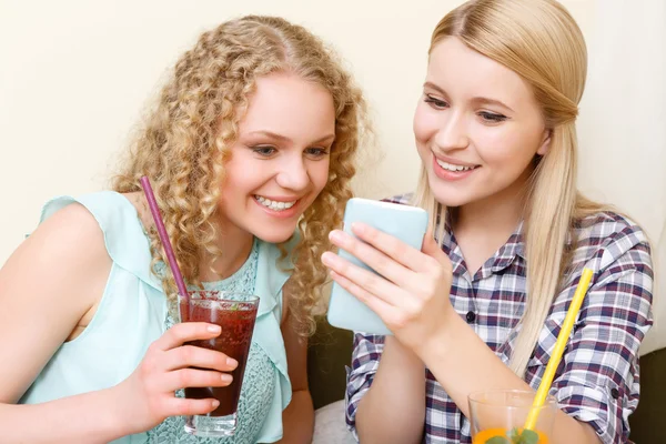 Pair of women looking at phone in cafe