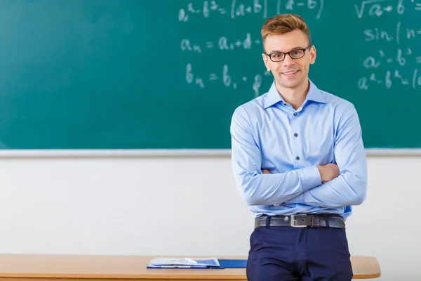 Young male professor is posing at the desk.