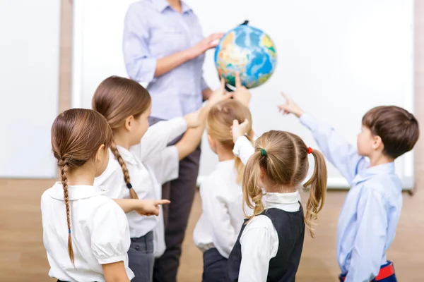 Group of children and teacher holding a globe.