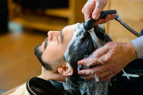 Professional barber washing hair of the client