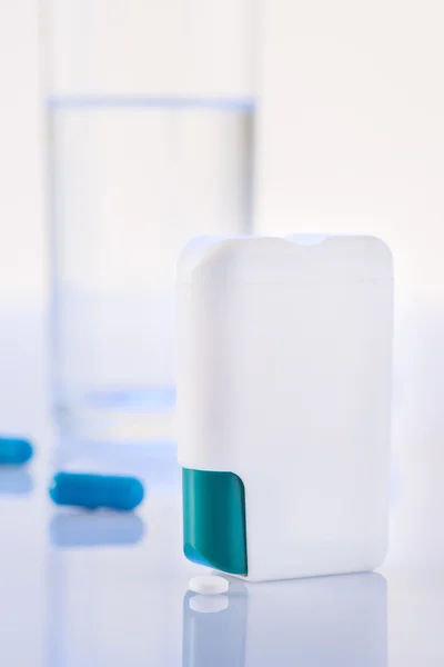 Pill dispenser and glass of water on the surface.