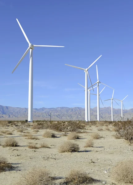 Alternative energy concept, wind turbine in desert landscape with blue sky