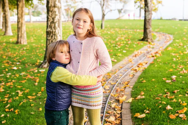 Two adorable kids playing in the park on a nice autumn day