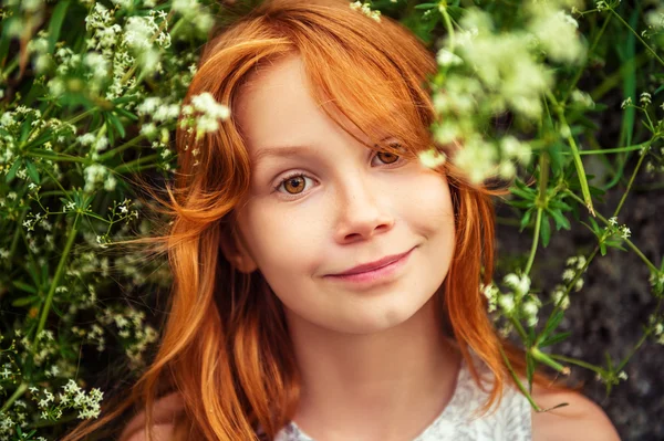 Close up outdoor portrait of adorable little girl of 8-9 years old . Red hair sweet young girl of 7-8 years old.