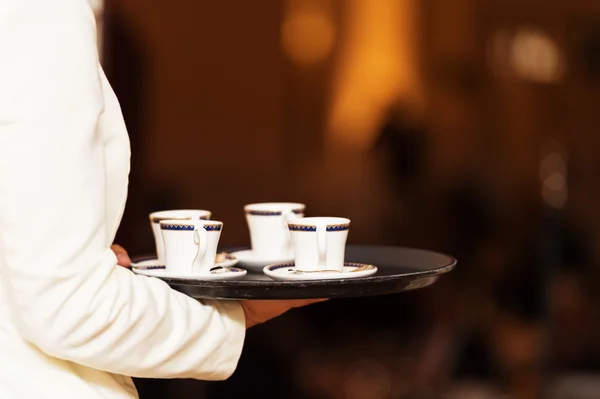Waiter carrying tray with coffee cups on some festive event, party or wedding reception