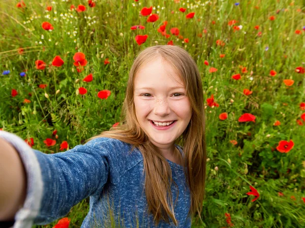 Funny little girl doing selfie in poppy field. Preteen 8-9 years old girl taking photos of herself