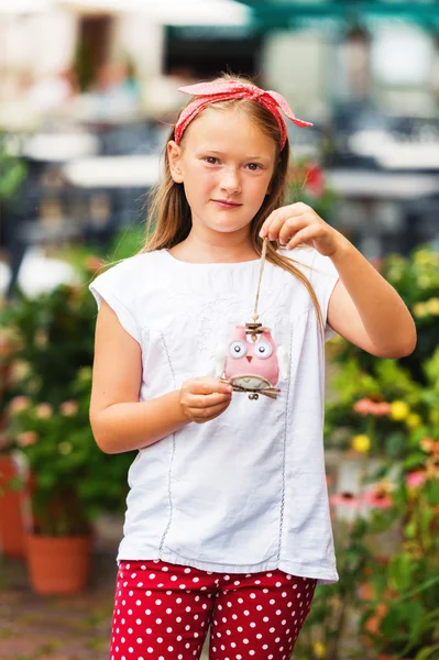 Outdoor fashion portrait of a cute little girl of 8 years old, wearing funny headband, white tee shirt and polka dot trousers