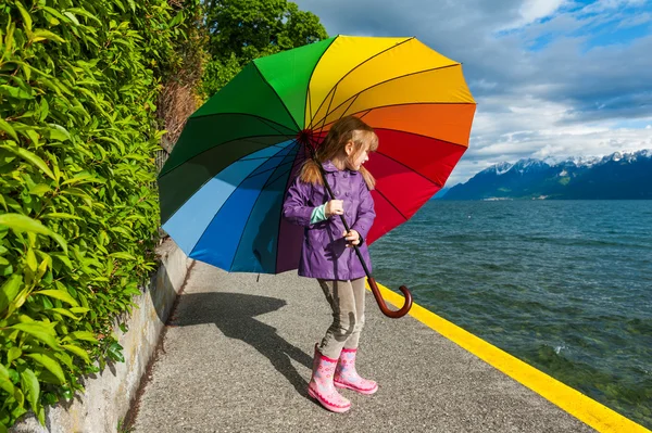 Outdoor portrait of a cute little girl, wearing rain jacket and boots