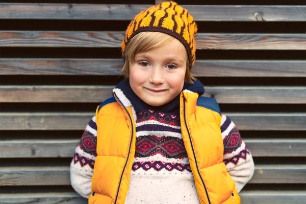 Outdoor portrait of a cute little boy, wearing warm pullover and yellow vest