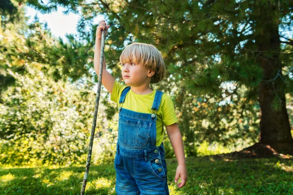 Little boy playing outdoors on a nice sunny summer day wearing denim overalls