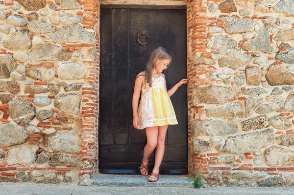 Outdoor fashion portrait of a cute little girl wearing yellow dress